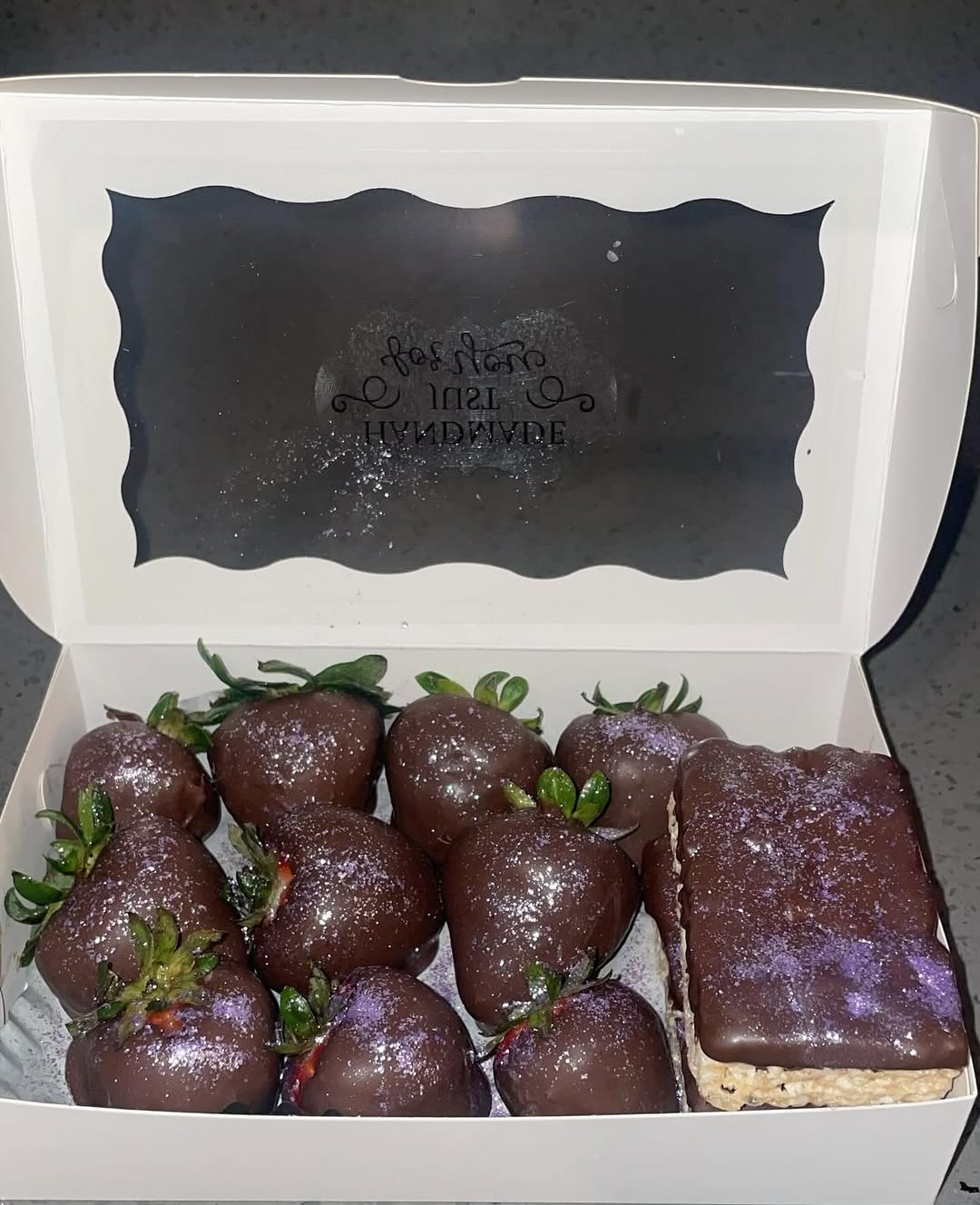 Assorted box of eight dark chocolate strawberries and two Rice Krispie bars, all dusted with a distinctive purple lavender edible shimmer.