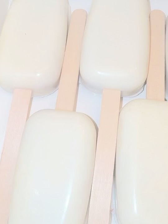 Close-up of smooth white chocolate cakesicles with a warm ivory tone, showcasing the clean minimalist coating technique.
