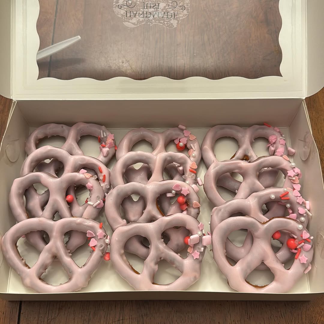 A dozen lavender chocolate-covered pretzels decorated with Valentine's sprinkle mix of hearts, stars, pink jimmies, and pearl balls.