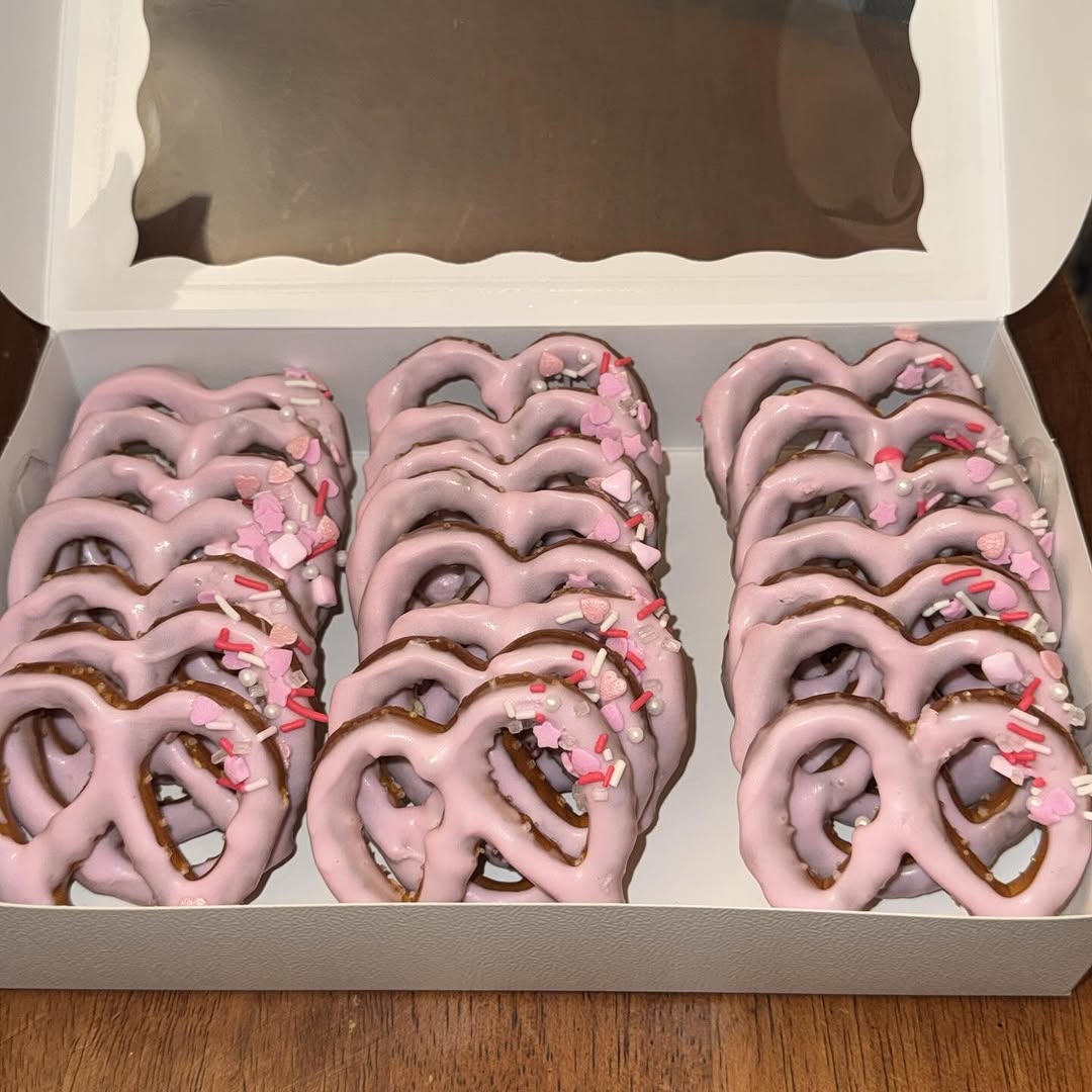Large box of pink-lavender chocolate-dipped pretzels standing upright, decorated with Valentine's heart and star sprinkle mix.