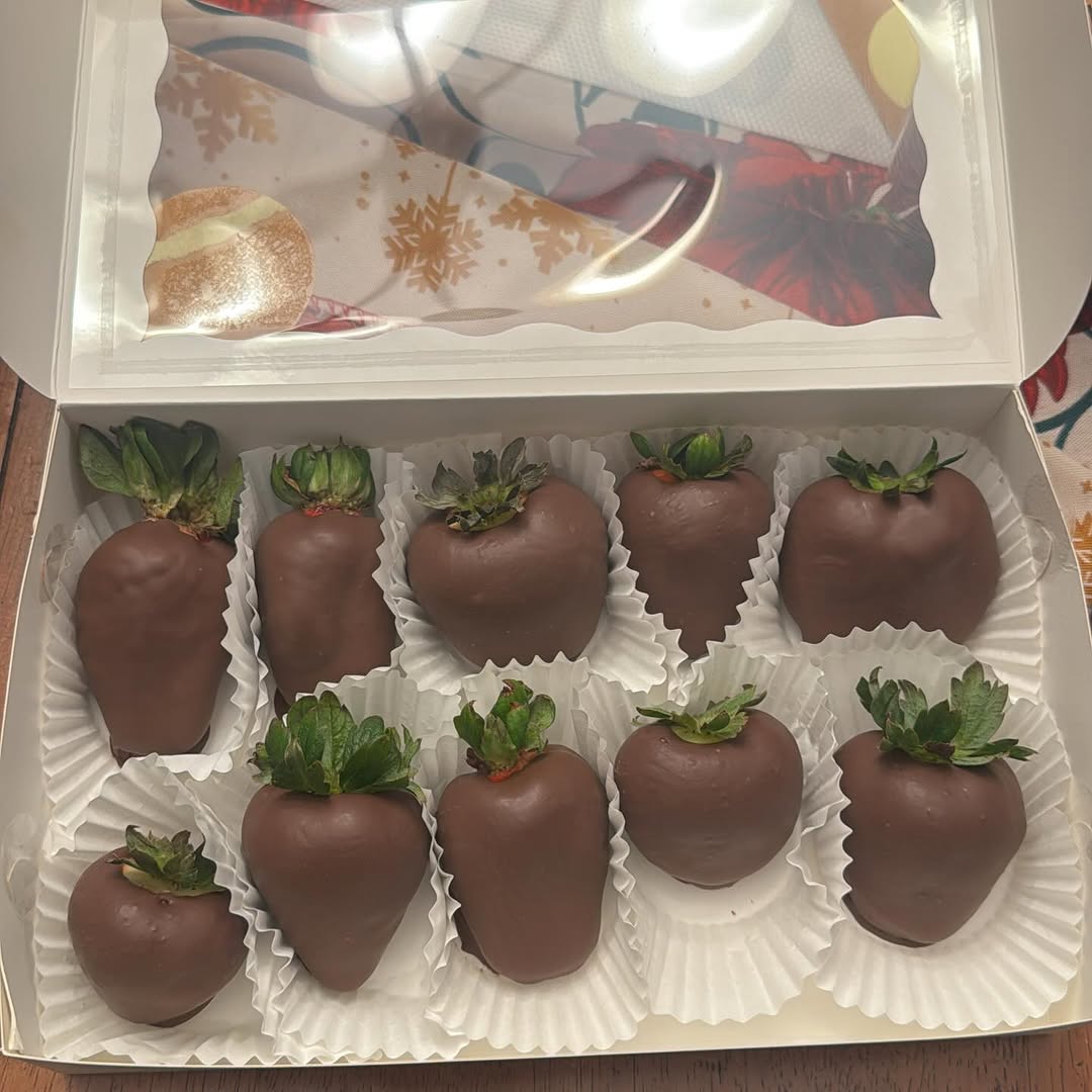 Ten classic milk chocolate-covered strawberries in a white bakery box with a holiday snowflake tablecloth visible behind.