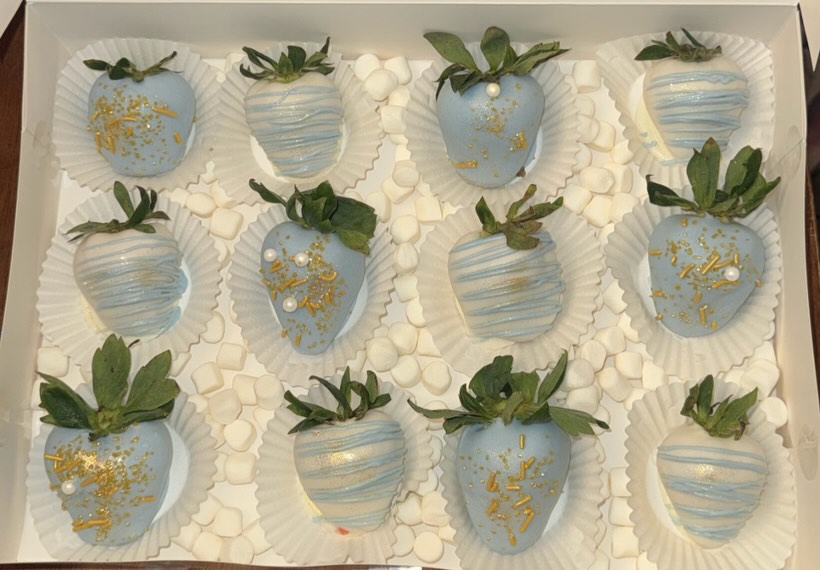 A dozen baby blue strawberries with luxurious gold leaf flakes, white drizzle, gold drizzle, and white pearl sprinkle accents in a white bakery box.