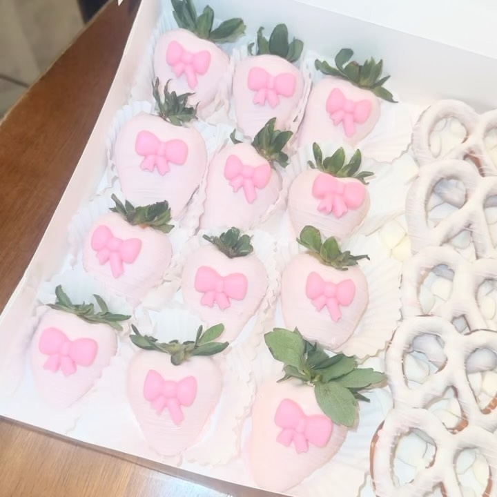 Close-up of pink chocolate strawberries each adorned with a carefully placed pink fondant bow, with smooth even coating and a romantic aesthetic.
